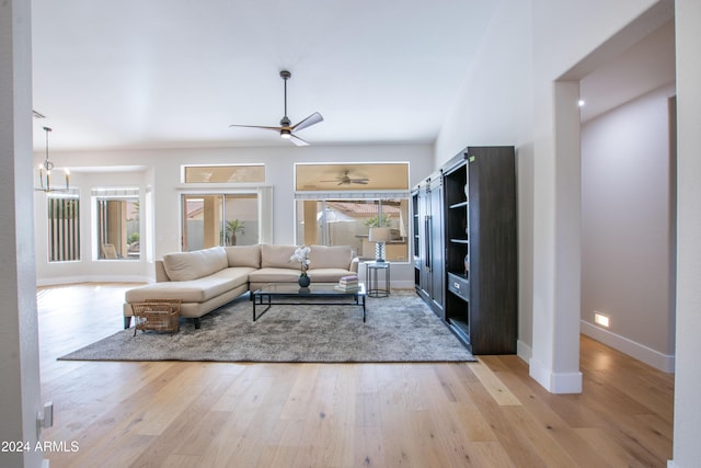 living room featuring ceiling fan with notable chandelier and light wood-type flooring