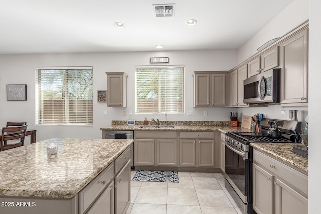 kitchen featuring sink, a wealth of natural light, light stone countertops, and appliances with stainless steel finishes