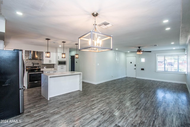 kitchen featuring pendant lighting, white cabinets, a kitchen island, wall chimney exhaust hood, and appliances with stainless steel finishes