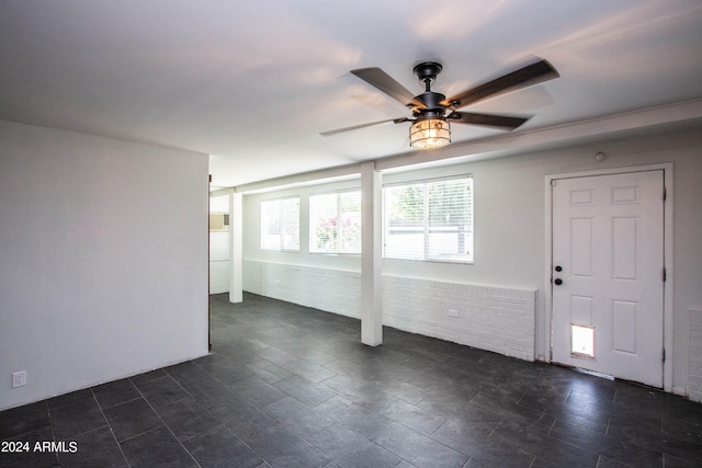 spare room featuring ceiling fan and brick wall