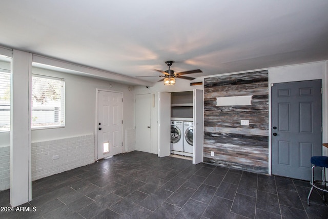 washroom featuring wooden walls, ceiling fan, and washer and dryer