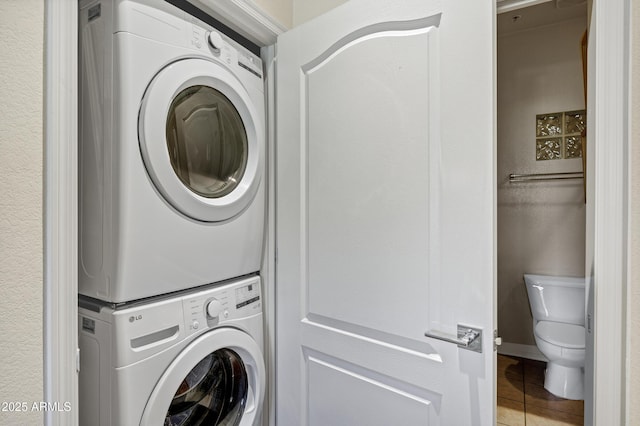 washroom featuring stacked washer / dryer, laundry area, and tile patterned floors