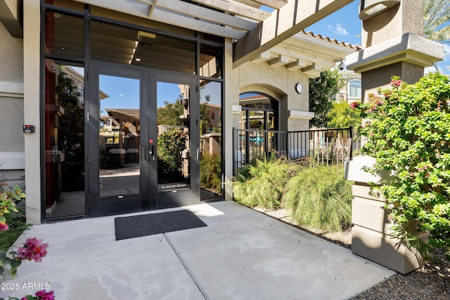 doorway to property with stucco siding, a tiled roof, and french doors