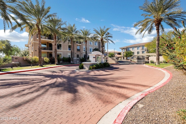 view of road featuring curbs, a gated entry, sidewalks, and a gate