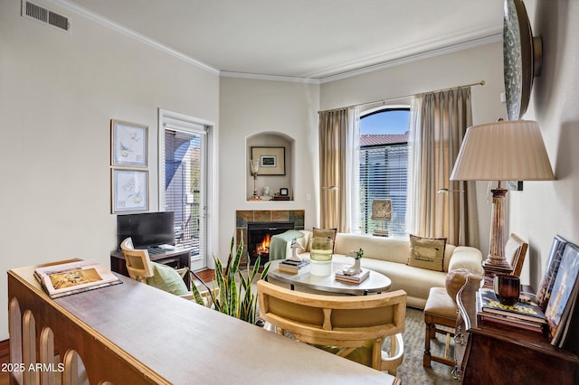 living area featuring visible vents, crown molding, and a tile fireplace