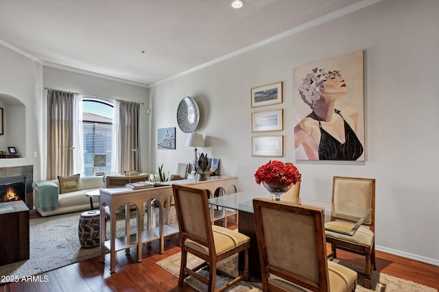 dining space featuring ornamental molding, a tile fireplace, wood finished floors, and baseboards