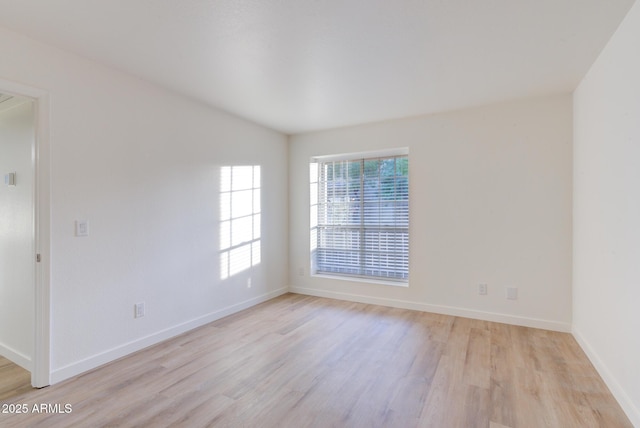 empty room featuring light wood-type flooring and baseboards