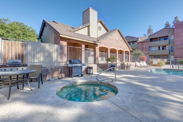 community pool featuring a community hot tub, a patio area, fence, and area for grilling