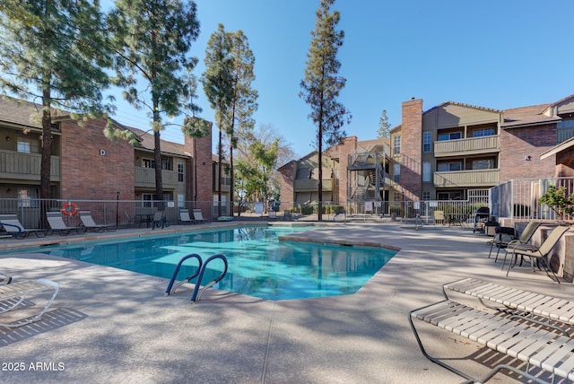 community pool featuring a residential view, fence, and a patio