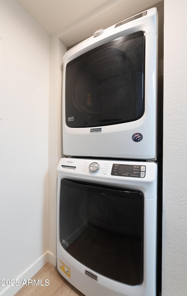 interior details featuring baseboards, stacked washer / dryer, and wood finished floors