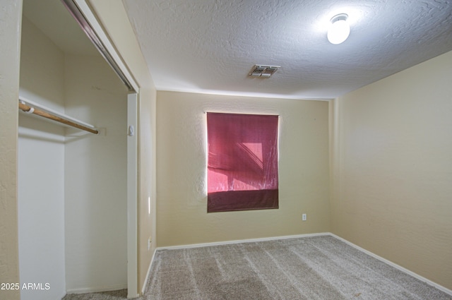 unfurnished bedroom with a textured ceiling, carpet floors, visible vents, baseboards, and a closet