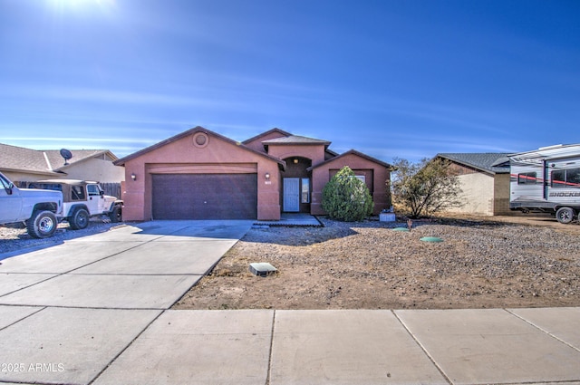 view of front of home featuring driveway, an attached garage, and stucco siding