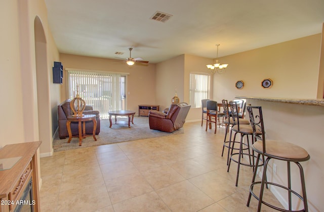 living room featuring light tile patterned floors and ceiling fan with notable chandelier