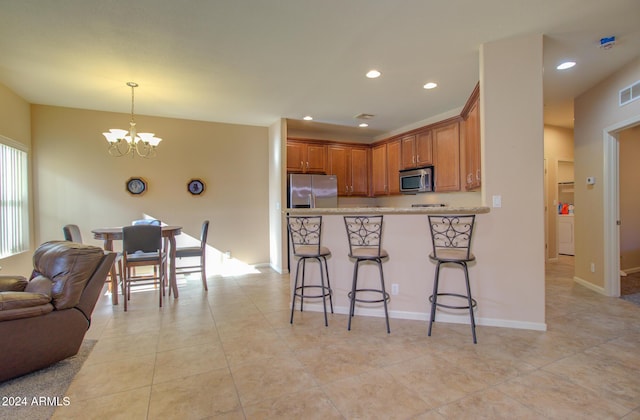 kitchen with a breakfast bar area, decorative light fixtures, kitchen peninsula, stainless steel appliances, and a chandelier