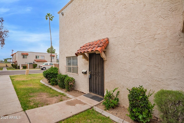doorway to property featuring stucco siding and a tiled roof