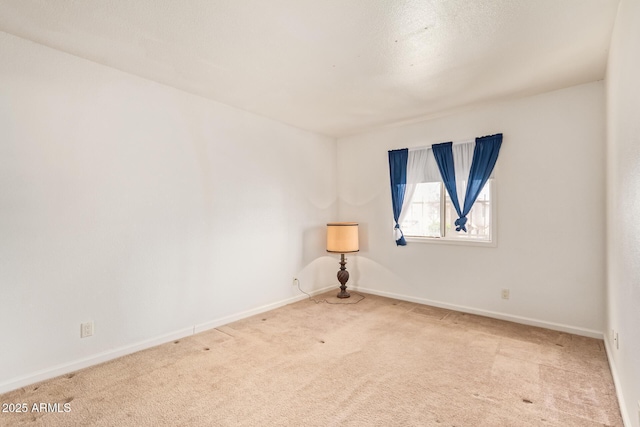 spare room with light colored carpet and baseboards