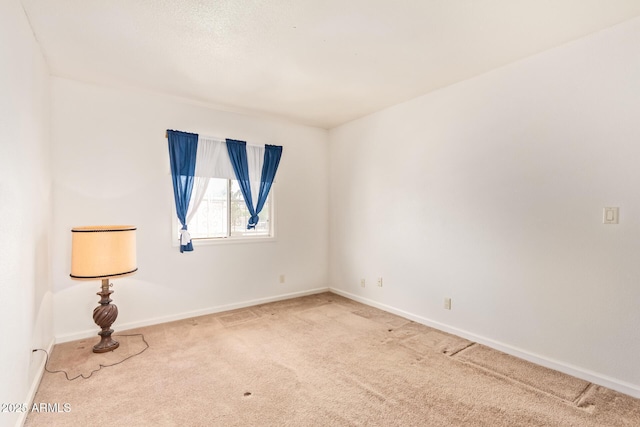 empty room featuring carpet floors and baseboards