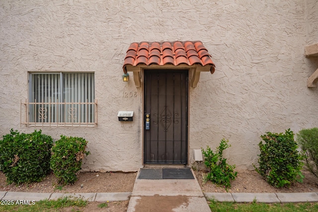 doorway to property with stucco siding and a tile roof