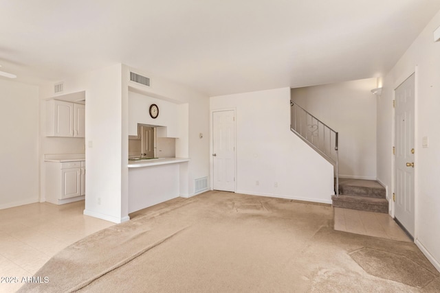 unfurnished living room with stairs, baseboards, and light carpet