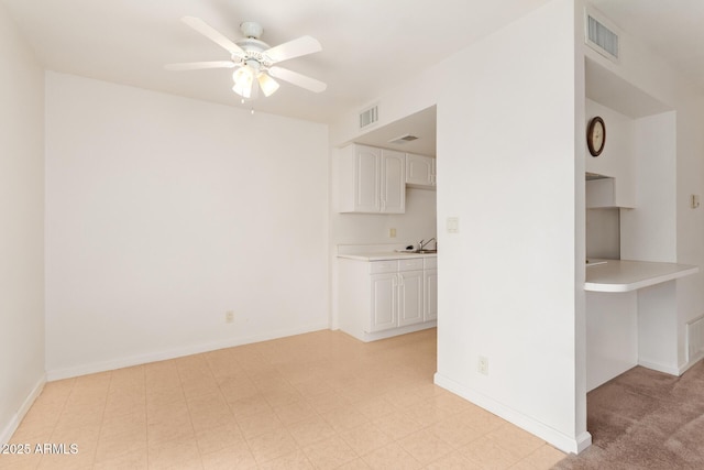 unfurnished living room featuring ceiling fan, a sink, and baseboards