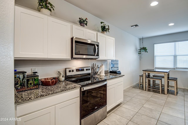 kitchen featuring visible vents, stainless steel appliances, dark stone countertops, and white cabinetry