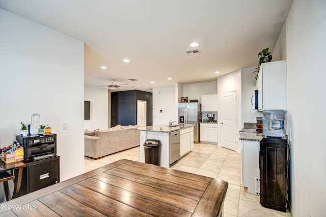 kitchen with visible vents, an island with sink, open floor plan, stainless steel appliances, and white cabinetry