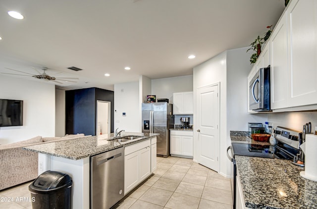 kitchen with a center island with sink, appliances with stainless steel finishes, open floor plan, white cabinets, and a sink