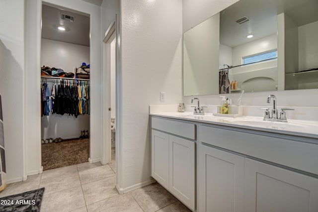 bathroom featuring double vanity, visible vents, a sink, and tile patterned floors