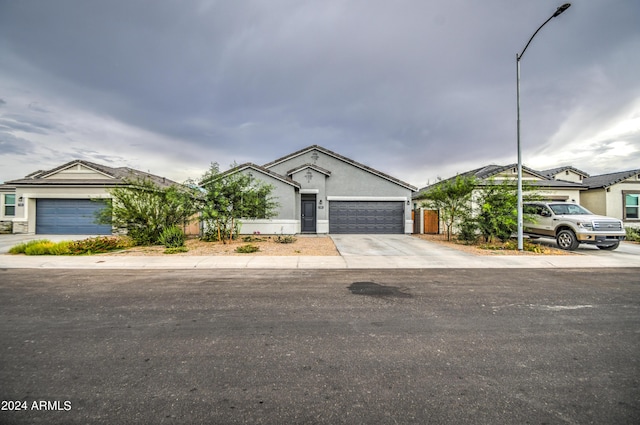 ranch-style home featuring concrete driveway, an attached garage, and stucco siding