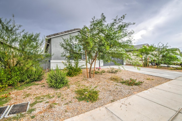 view of front of home featuring concrete driveway, a tiled roof, and stucco siding