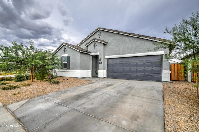 view of front of property featuring stucco siding, concrete driveway, fence, a garage, and a tiled roof