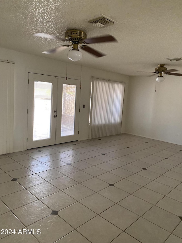 spare room with french doors, a textured ceiling, and light tile patterned floors