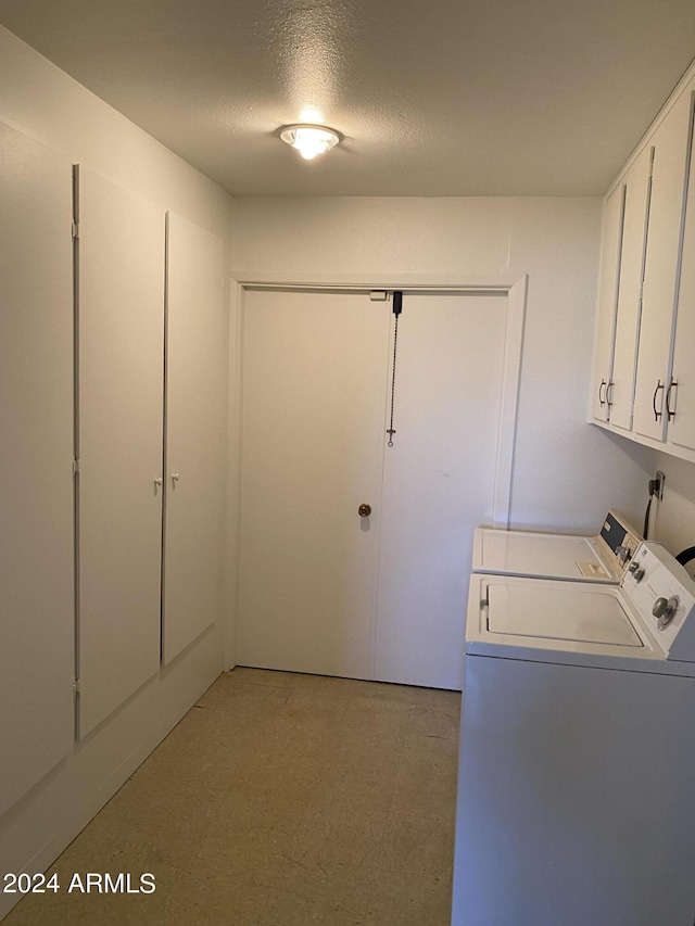 clothes washing area featuring washer and dryer, cabinets, and a textured ceiling