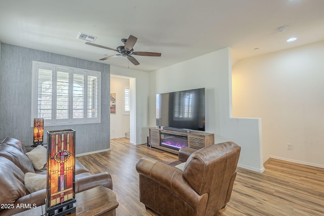 living room with visible vents, baseboards, a ceiling fan, light wood-style flooring, and recessed lighting