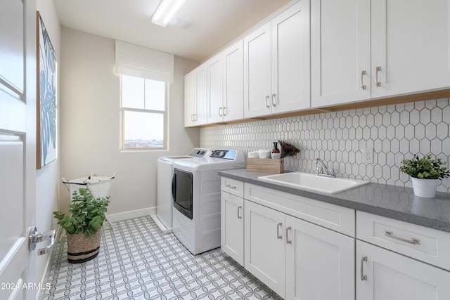 laundry area with baseboards, cabinet space, washing machine and clothes dryer, and a sink