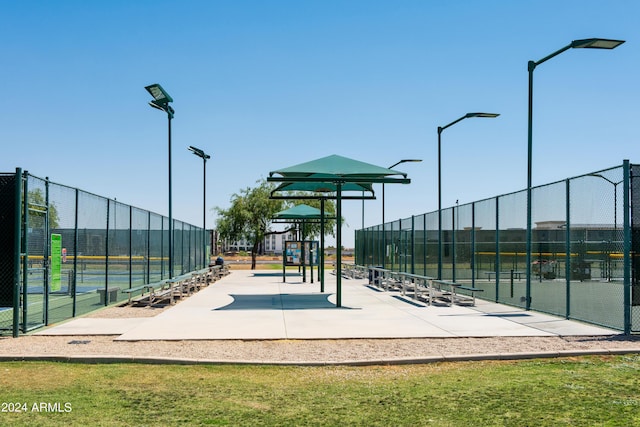 surrounding community with a tennis court, fence, and playground community