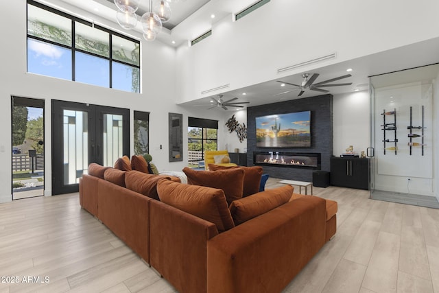 1807 E Campbell Ave, Phoenix, AZ 85016 - living area featuring light wood-style flooring, a glass covered fireplace, a ceiling fan, a towering ceiling, and french doors