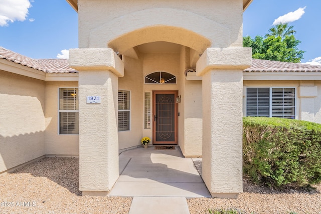 property entrance featuring a tiled roof and stucco siding