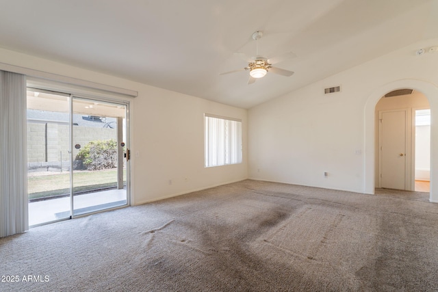 carpeted spare room with visible vents, lofted ceiling, ceiling fan, plenty of natural light, and arched walkways