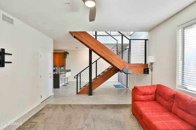 living room with ceiling fan, sink, and light carpet