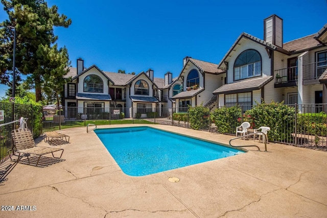 pool featuring a residential view, a patio, and fence