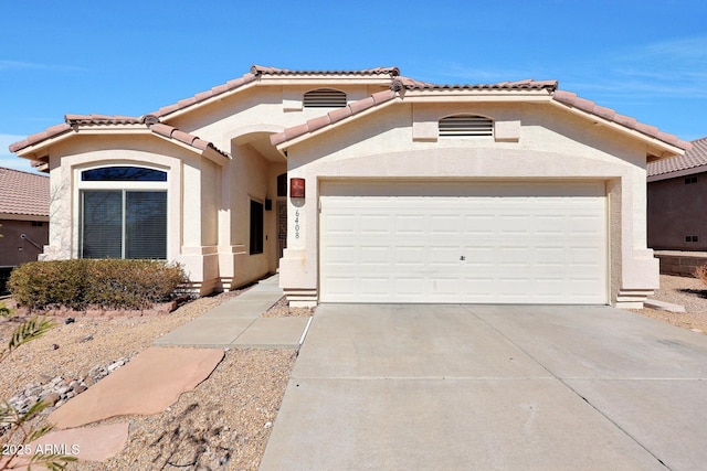 mediterranean / spanish-style house featuring concrete driveway, a tiled roof, an attached garage, and stucco siding