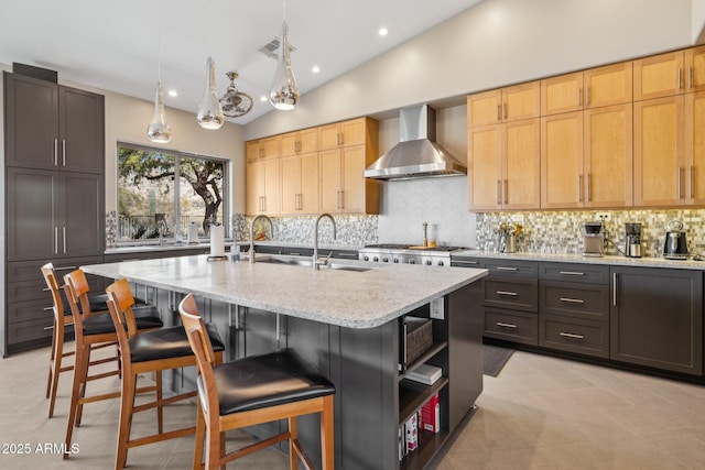 kitchen featuring light stone counters, a breakfast bar area, open shelves, tasteful backsplash, and wall chimney range hood