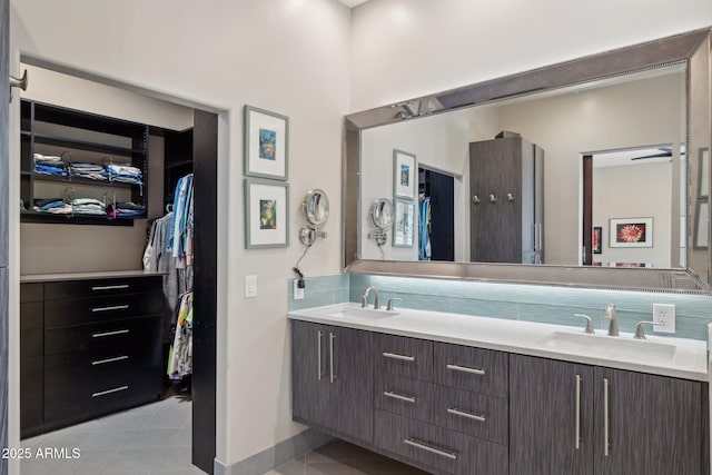 bathroom with double vanity, tasteful backsplash, a spacious closet, and a sink