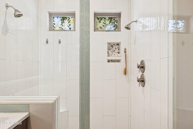 full bath with a tile shower and vanity