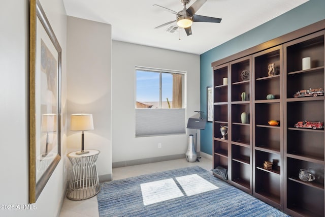 living area with tile patterned flooring, visible vents, ceiling fan, and baseboards