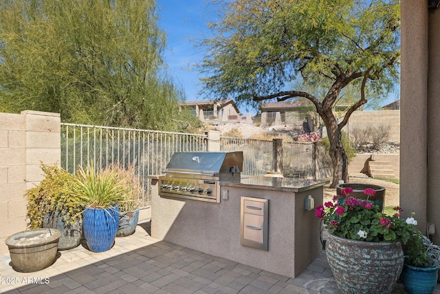 view of patio featuring exterior kitchen, fence, and grilling area