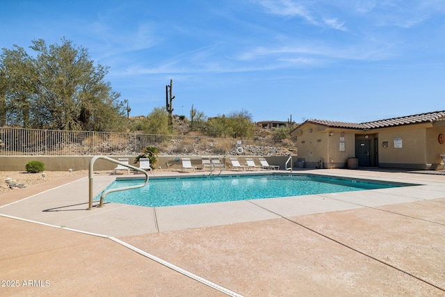 community pool with a patio area and fence