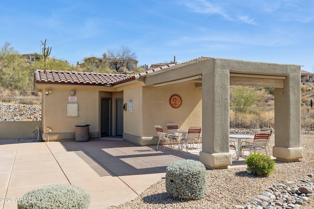 back of house featuring stucco siding, a tiled roof, fence, and a patio