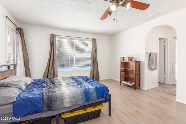 2031 W Gila Ln, Chandler, AZ 85224 - bedroom with arched walkways, light wood-style flooring, a textured ceiling, ceiling fan, and baseboards